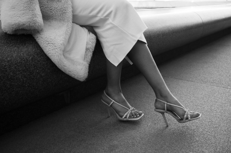 Kobieta w eleganckich botkach na szpilce siedząca na szezlongu