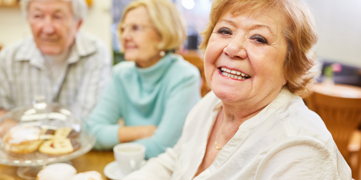 Uśmiechnięte seniorki siedzące przy stole w wygodnych butach zdrowotnych