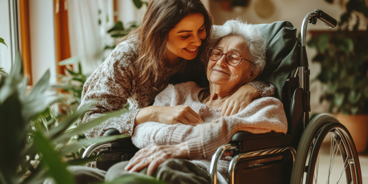 Kobieta przytulająca uśmiechniętą starszą osobę na wózku inwalidzkim