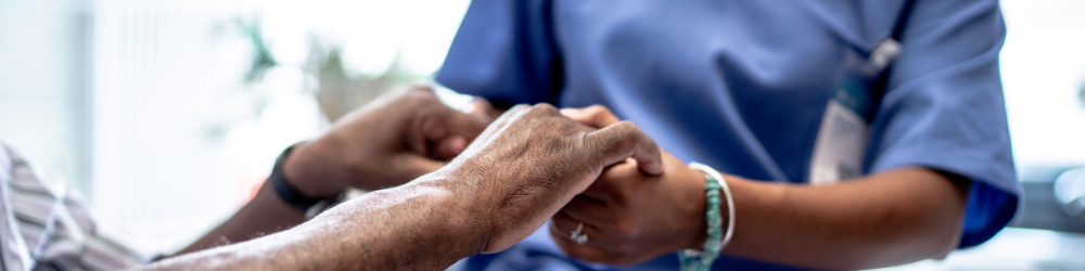 Pielęgniarka trzymająca za rękę starszą pacjentkę